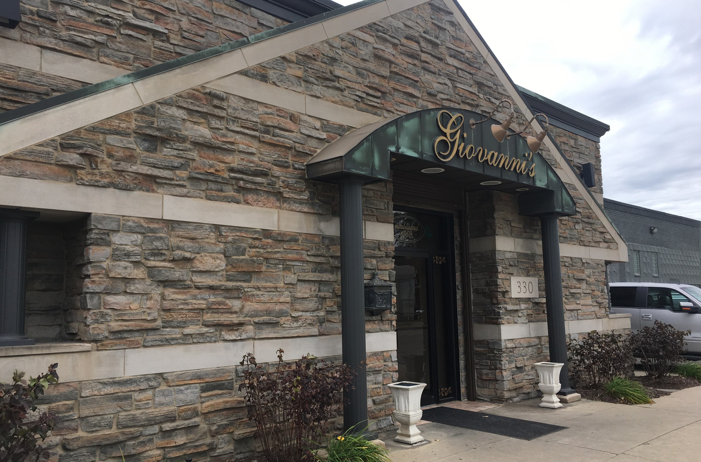 Giovanni’s restaurant has a stone exterior with columns and a green sign with gold writing.